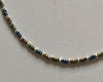 May include: A silver, brown, and blue beaded necklace. The beads are small and round.