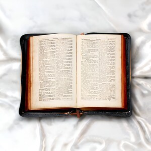 May include: An open leather-bound book with a brown cover and gold-gilded edges. The pages are filled with text in a traditional font. The book is open to a page with the title "Psalms" and the text "The Book of Psalms".