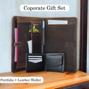 May include: A brown leather portfolio with a pen holder and a matching black leather wallet. The portfolio has a card slot and a pocket for documents. The wallet has a card slot and a billfold. The set is labelled "Corporate Gift Set" and "Portfolio + Leather Wallet".