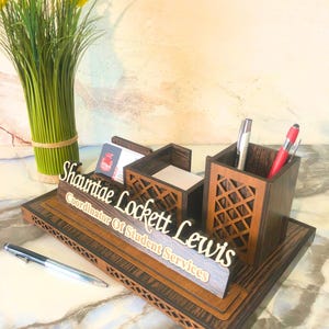 May include: Wooden desk organizer with a nameplate that reads "Shantae Lockett Lewis, Coordinator of Student Services". The organizer has compartments for pens, pencils, and business cards.