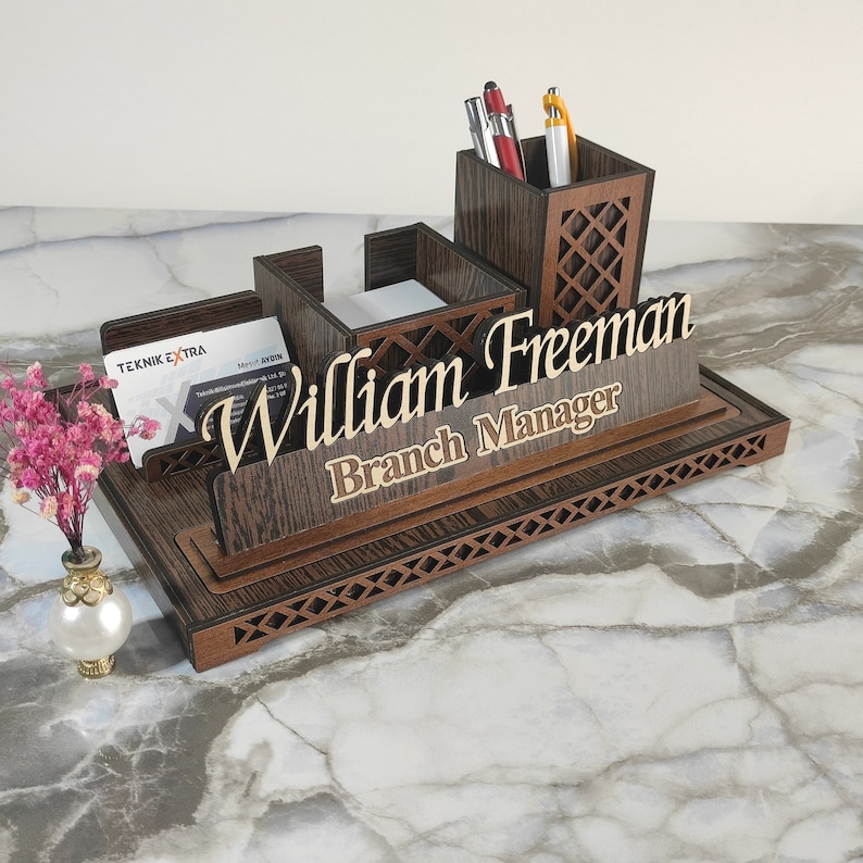 May include: Wooden desk organizer with a pen holder, note pad holder, and business card holder. The organizer has a personalized nameplate that reads "William Freeman Branch Manager".