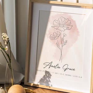 May include: A framed print with a watercolour background in shades of pink. A line drawing of two flowers is in the centre of the print. The text "Amelia Grace" is below the flowers, along with the date "March 8th, 2022", weight "8 lbs", length "19.5 inches", and time "2:00 A.M."