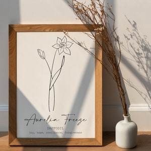 May include: A framed print featuring a black line drawing of a daffodil flower. The print includes the text "Aurelia Freeze" and "DAFFODIL" with the words "joy, hope, resilience, forgiveness" underneath.