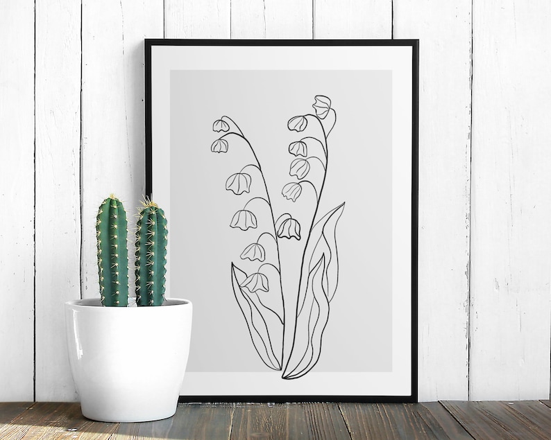 May include: A black and white line drawing of lily of the valley flowers in a simple, minimalist style. The drawing is on a light grey background and is framed in a black frame.