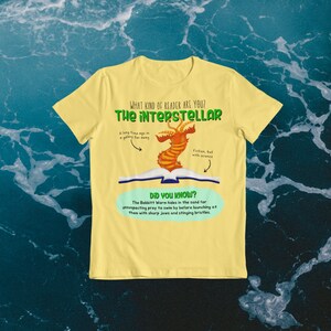 May include: Yellow t-shirt with a graphic of a book with a worm-like creature emerging from it. The text on the shirt reads "What kind of reader are you? The interstellar. A long time ago in a galaxy far away. Fiction, but with science. Did you know? The Babbitt Worm hides in the sand for unsuspecting prey to swim by before launching at them with sharp jaws and stinging bristles."
