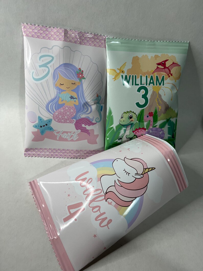 May include: Three pink and white treat bags with different designs. One bag features a mermaid with the name "Faith" and the number "3". Another bag features a dinosaur with the name "William" and the number "3". The third bag features a unicorn with the name "Willow" and the number "4".