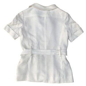 May include: A white linen short-sleeved shirt with a collar and a belt.