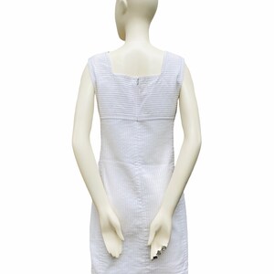 May include: A white sleeveless dress with a striped pattern and a zipper closure in the back.