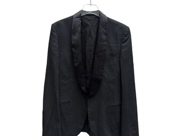 May include: A black tuxedo jacket with a satin lapel. The jacket is hanging on a hanger.