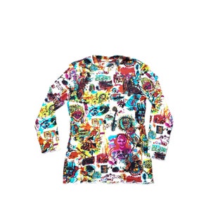 Może przedstawiać: Koszulka z długim rękawem z żywym, całopowierzchniowym nadrukiem. Projekt przedstawia kolaż kolorowych ilustracji, w tym twarzy, symboli i tekstu, na białym tle. Wz&oacute;r koszulki zawiera odcienie czerwieni, ż&oacute;łci, niebieskiego i czerni.