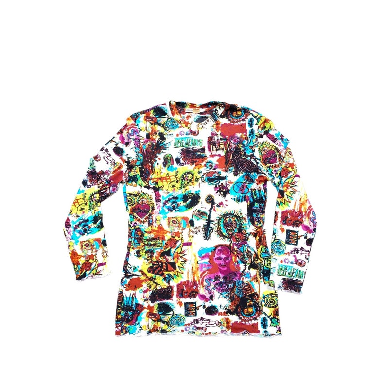 Może przedstawiać: Koszulka z długim rękawem z żywym, całopowierzchniowym nadrukiem. Projekt przedstawia kolaż kolorowych ilustracji, w tym twarzy, symboli i tekstu, na białym tle. Wz&oacute;r koszulki zawiera odcienie czerwieni, ż&oacute;łci, niebieskiego i czerni.
