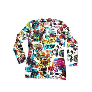 Może przedstawiać: Biała koszulka z długim rękawem z żywym, całopowierzchniowym nadrukiem z abstrakcyjną grafiką w kolorach czerwonym, niebieskim, ż&oacute;łtym i czarnym. Koszulka ma okrągły dekolt, a na g&oacute;rnej części plec&oacute;w widoczny jest napis "JPG JIAN'S".