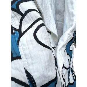 Peut inclure: Chemise en coton blanc avec un imprim&eacute; abstrait bleu et noir. La chemise a un col boutonn&eacute; et une manche longue.