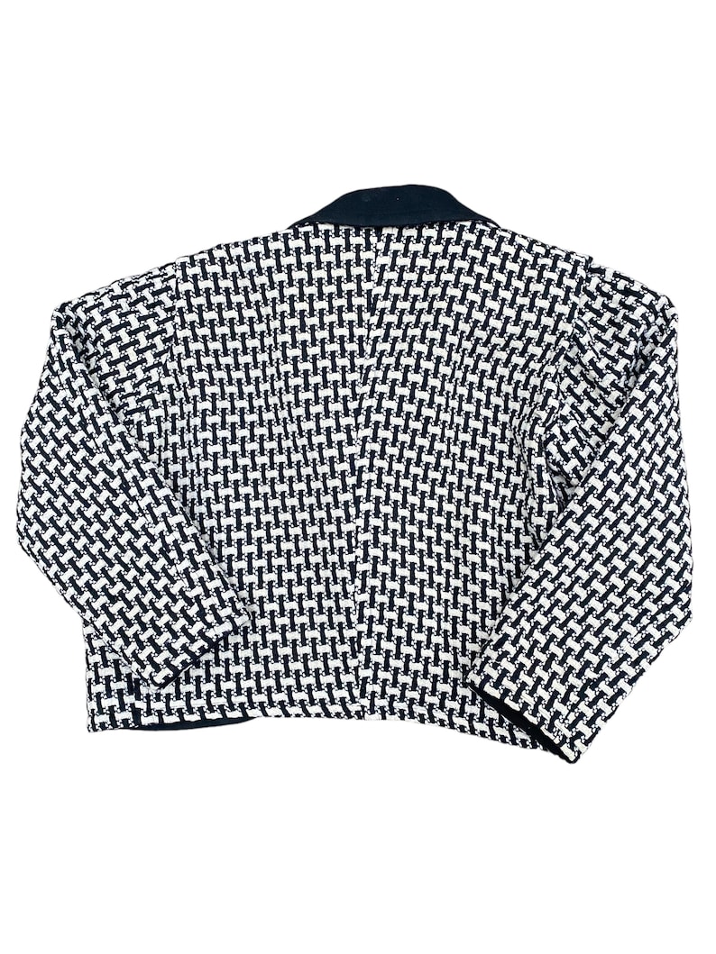 May include: A black and white patterned blazer with a black collar. The blazer has a cropped length and long sleeves.