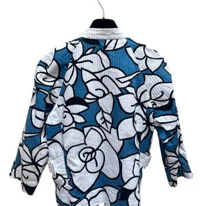 Peut inclure: Une veste matelass&eacute;e bleu et blanc avec un imprim&eacute; floral. La veste a un col montant et des manches longues.
