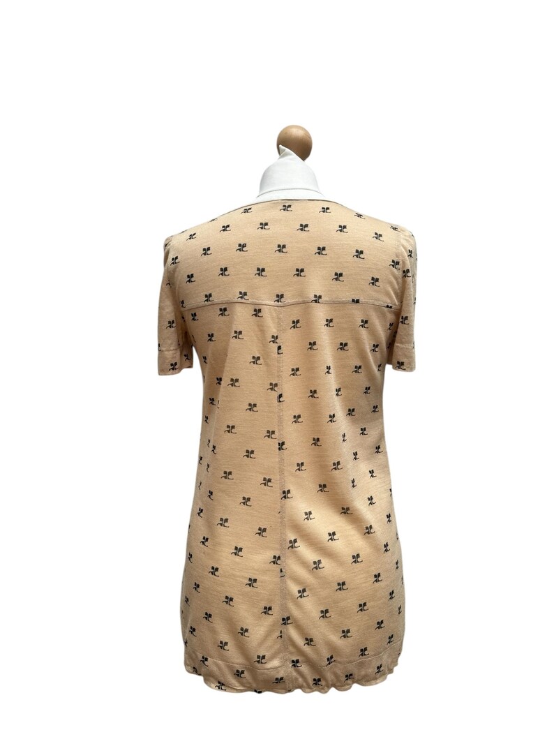 May include: A peach-colored short-sleeved dress with a black and white print of a repeated pattern. The dress has a round neckline and a slightly flared skirt.
