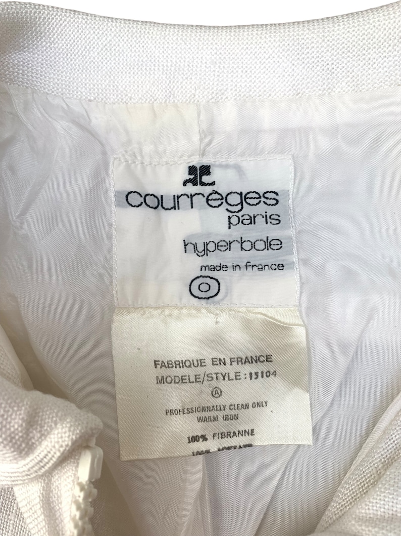 May include: White label with black text reading "Courreges Paris hyperbole made in France" and "Fabrique en France Modele/Style: 15104 Professionally clean only Warm iron 100% FIBRANNE".
