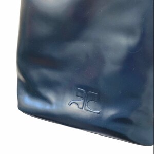 May include: Close-up of a dark blue leather bag with the letters "RC" embossed on the front.