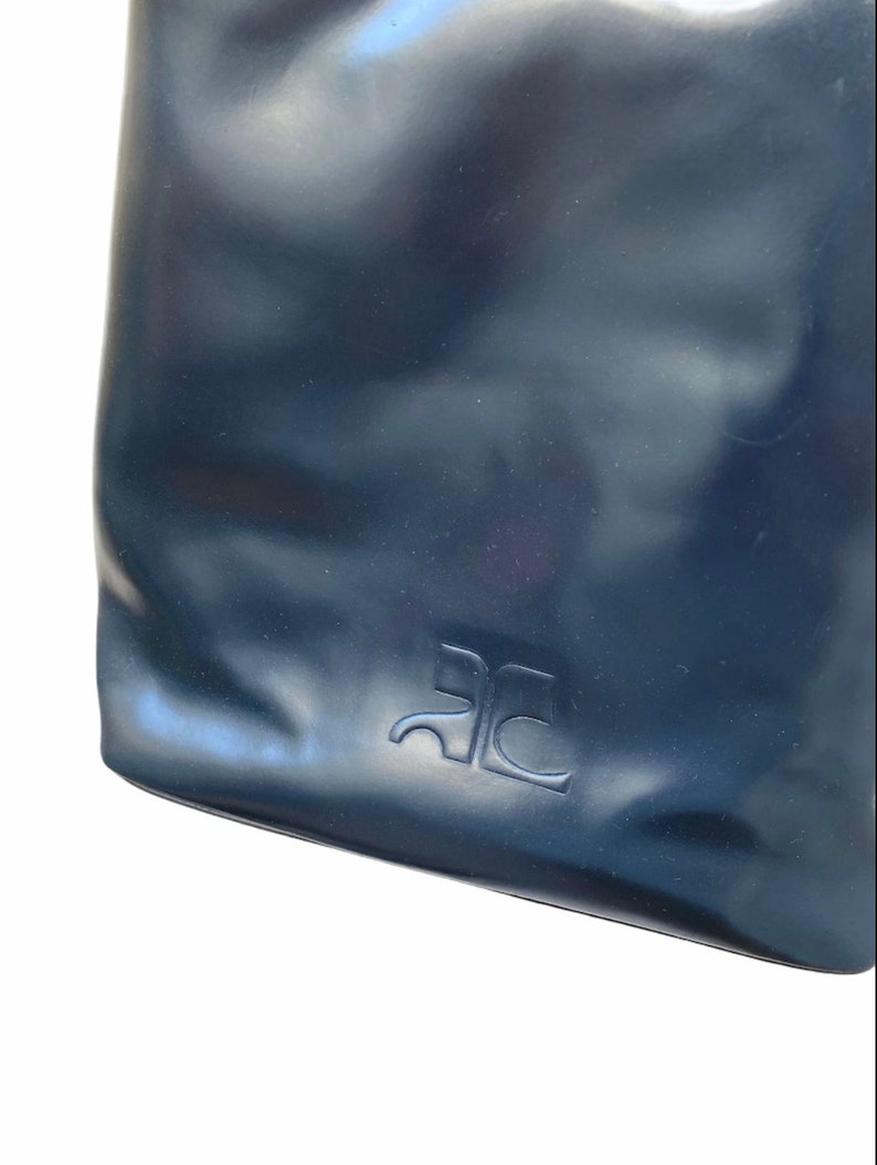 May include: Close-up of a dark blue leather bag with the letters "RC" embossed on the front.