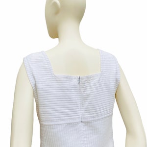 May include: White sleeveless dress with a square neckline and a zipper closure in the back. The dress has a striped pattern.