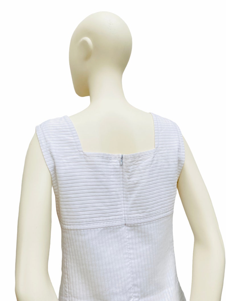 May include: White sleeveless dress with a square neckline and a zipper closure in the back. The dress has a striped pattern.