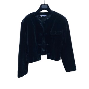 May include: A black velvet cropped jacket with a button closure and a pocket on the left side.