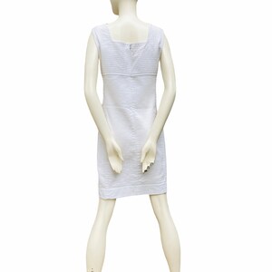 May include: A white sleeveless dress with thin vertical stripes. The dress has a square neckline and a zipper closure in the back.