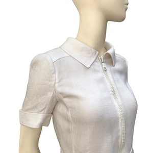 May include: White linen dress with a zipper closure and a belt. The dress has short sleeves and a collared neckline.