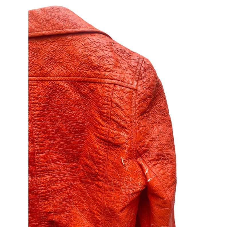 May include: A bright orange leather jacket with a textured surface. The jacket has a classic design with a collar and long sleeves.