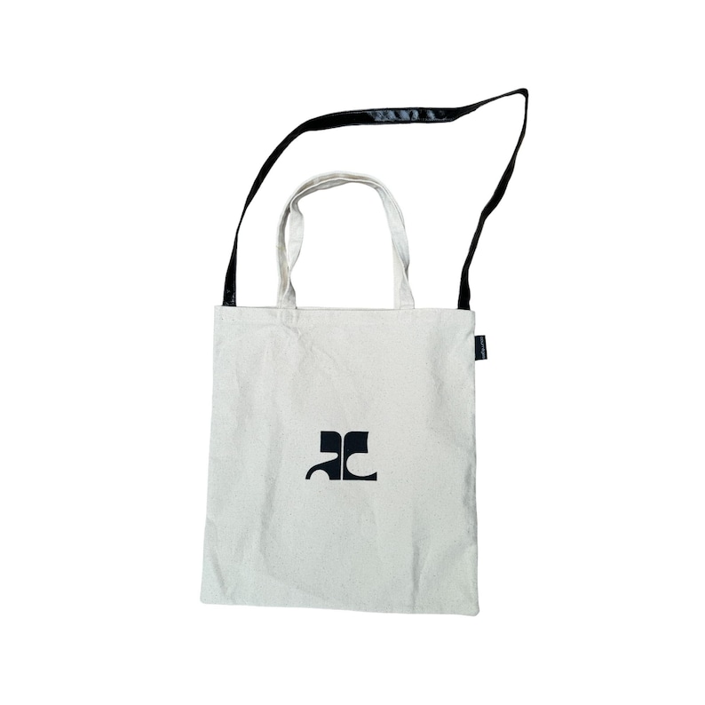 May include: A white canvas tote bag with a black adjustable shoulder strap. The bag has a black logo that says "AC" on the front.