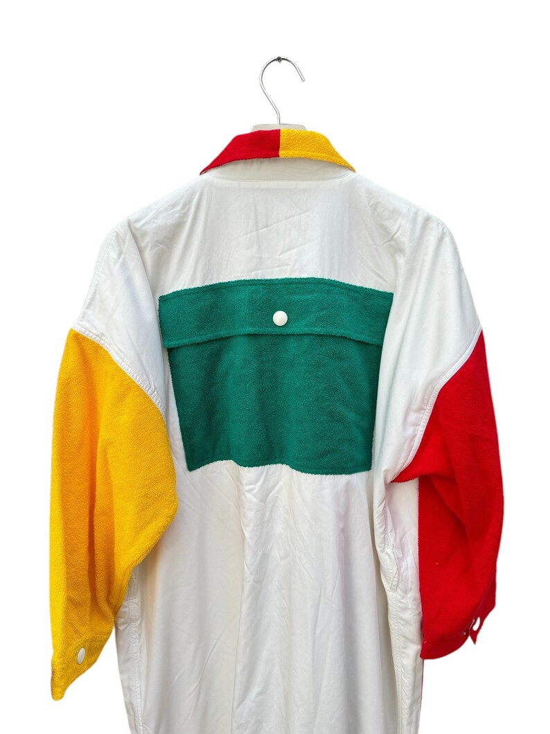 Puede incluir: Camisa blanca de manga larga con un dise&ntilde;o de bloques de color verde, amarillo y rojo. La camisa tiene un bolsillo de parche en la espalda y un cierre de bot&oacute;n.