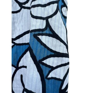 Puede incluir: Tela blanca con un patr&oacute;n floral azul y negro. La tela tiene una superficie texturizada y acanalada.