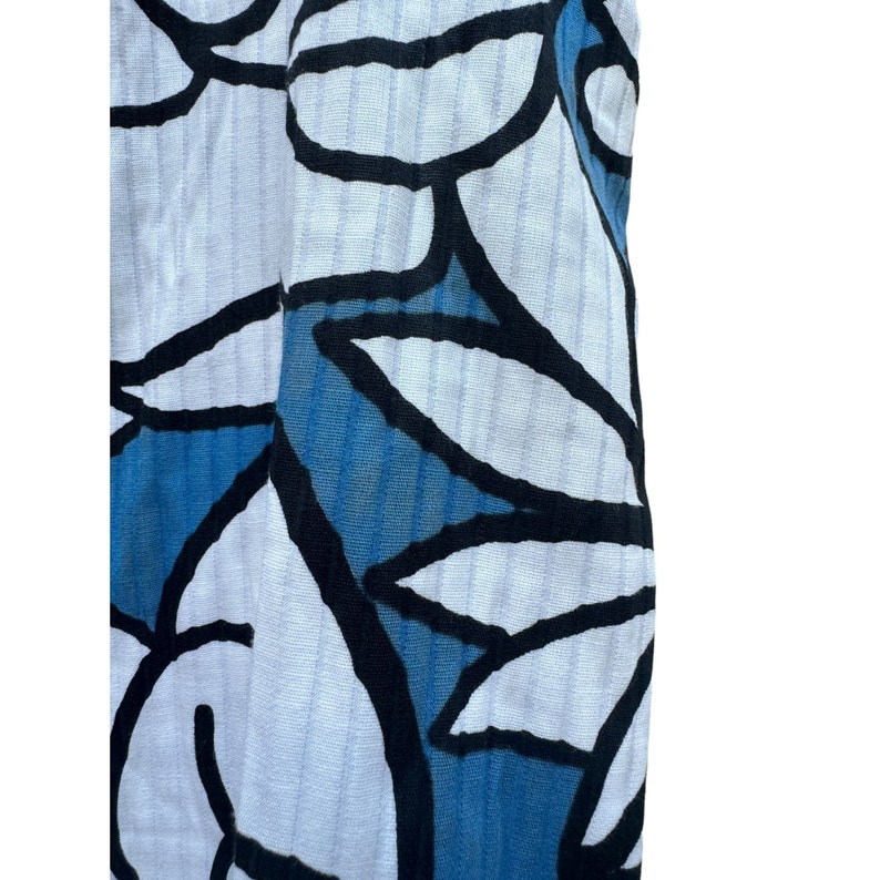 Puede incluir: Tela blanca con un patr&oacute;n floral azul y negro. La tela tiene una superficie texturizada y acanalada.