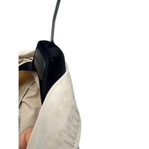 May include: A beige trench coat with a black velvet hanger. The coat has a collar and a button closure.