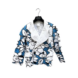 K&ouml;nnte beinhalten: Ein wei&szlig;-blauer Blazer mit floralem Muster, doppelreihiger Knopfleiste und gro&szlig;em Kragen. Der Blazer hat ein wei&szlig;es Futter und zwei Taschen.