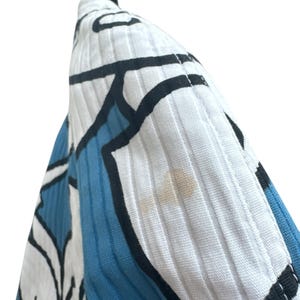 Peut inclure: Gros plan sur un tissu &agrave; motifs blancs et bleus avec des contours noirs. Le tissu a une surface textur&eacute;e et c&ocirc;tel&eacute;e.