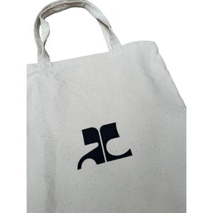 May include: A white canvas tote bag with a black "AC" logo printed on the front.