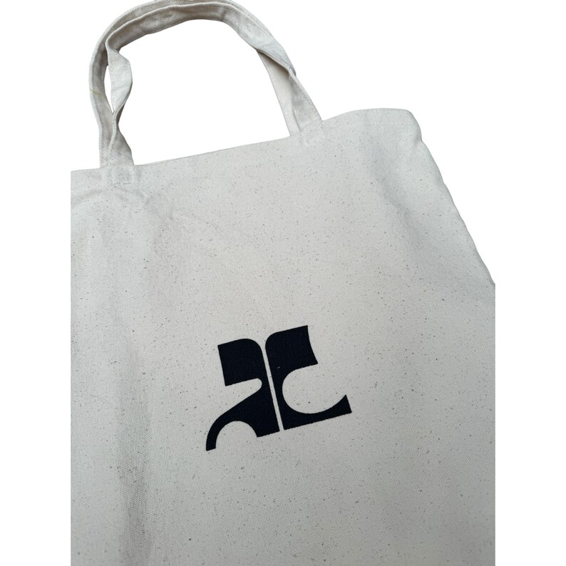 May include: A white canvas tote bag with a black "AC" logo printed on the front.