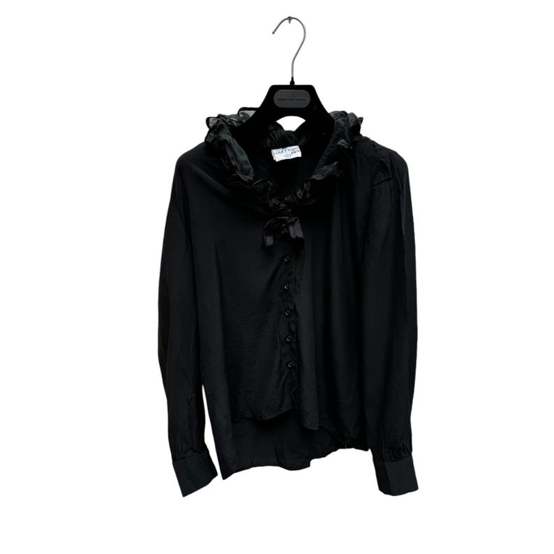 May include: A black long-sleeved blouse with a large ruffled collar and a bow tie. The blouse has a button-up front and long sleeves.