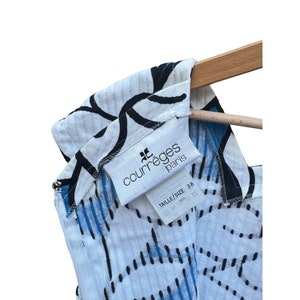 Puede incluir: Un vestido blanco sin mangas con un patr&oacute;n geom&eacute;trico negro y azul. El vestido tiene una etiqueta que dice "Courreges Paris" y "Taille/Size 38".