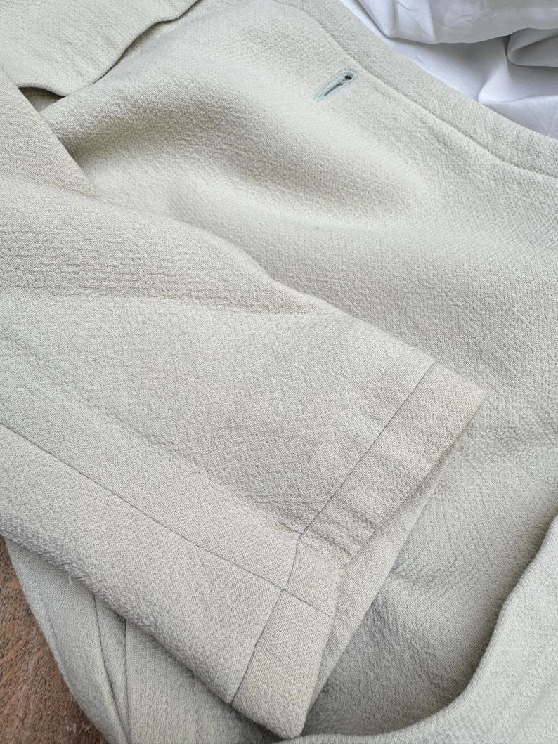 Puede incluir: Un blazer verde claro con tejido texturizado. El blazer tiene un cierre de un solo bot&oacute;n y un corte entallado. El pu&ntilde;o de la manga es visible, mostrando la calidad de las costuras.
