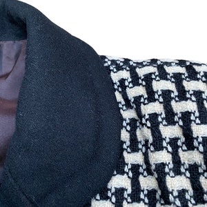 May include: Close-up of a black and white patterned jacket collar. The collar is made of a soft, textured fabric.