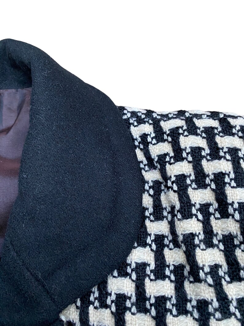 May include: Close-up of a black and white patterned jacket collar. The collar is made of a soft, textured fabric.