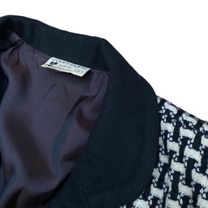 May include: Black and white patterned blazer with a black collar. The label inside the blazer reads "Courreges Paris" and "Made in France".