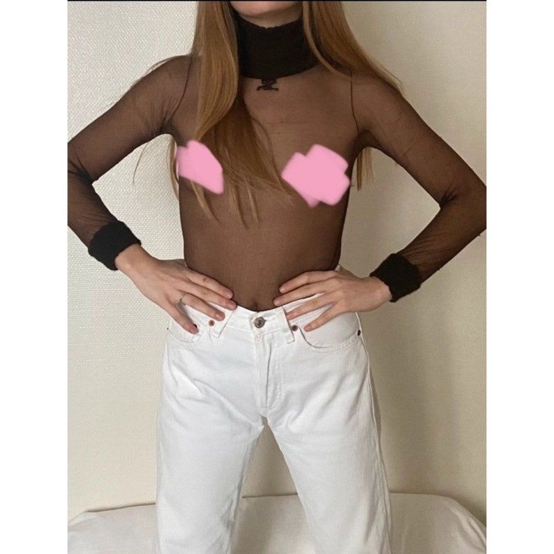 Op de afbeelding: Een zwart doorschijnend lang mouwtrui met een mock neck.