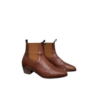 May include: A pair of brown leather ankle boots with a low heel. The boots have a pointed toe and a pull-on style.