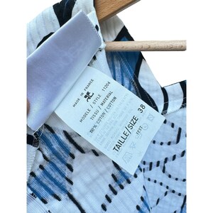 Puede incluir: Top de algod&oacute;n blanco y azul con estampado, con una etiqueta blanca que dice "Made in France", "Tissu / Material", "Modele / Style 11204", "100% Coton / Cotton", y "Taille / Size 38".