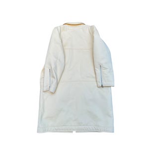 May include: A long, white coat with a yellow collar and zippered pockets on the sleeves.