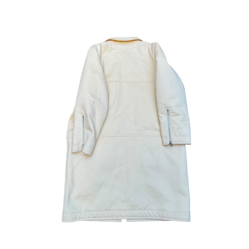 May include: A long, white coat with a yellow collar and zippered pockets on the sleeves.