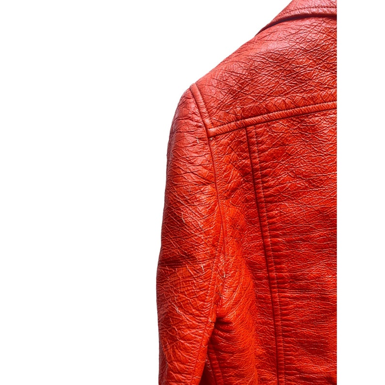 May include: Close-up of the back of a bright orange leather jacket. The jacket has a textured surface and a seam down the back.